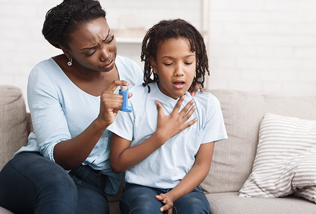 A parent helping a child use an inhaler at home.