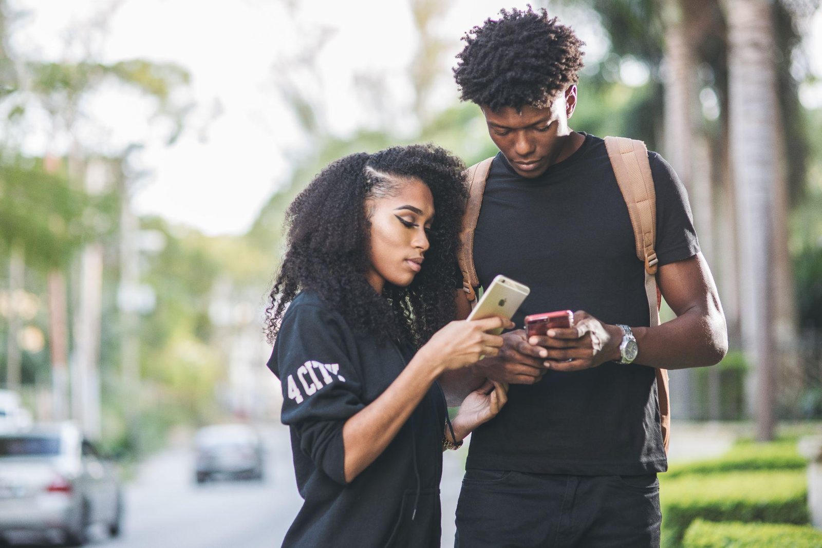 Two young people looking at a phone together on a city street.