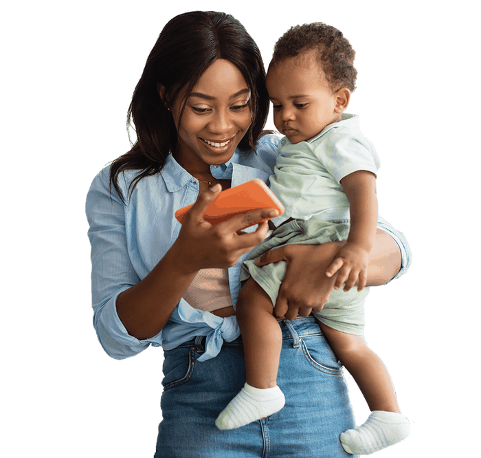 A mother holding her child, looking at her phone.